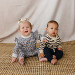 Two adorable babies wearing Blue Meadow Ruffle French Terry Set and cozy outfits, happy and ready for playtime.