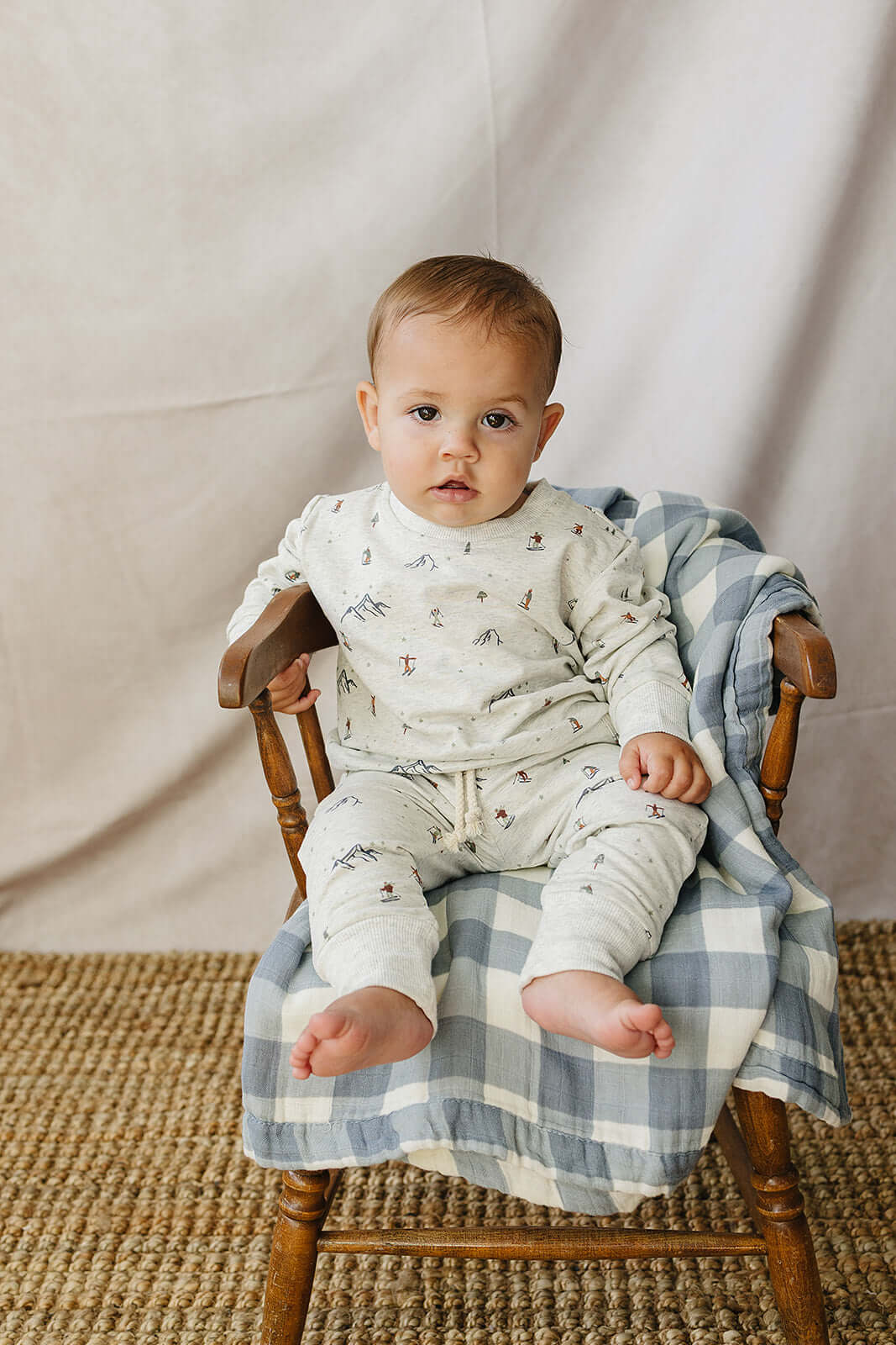Baby in Skier French Terry Set sitting comfortably on a chair, perfect for playtime or cozy days.
