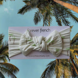 Palm | Bamboo Head Wrap | Milk & Baby | Made from silky-soft bamboo material, this adjustable head wrap features a sweet bow for added style. Perfect for babies and toddlers!One size fits most Print: Palm (a palm tree print on cream background) Material:
