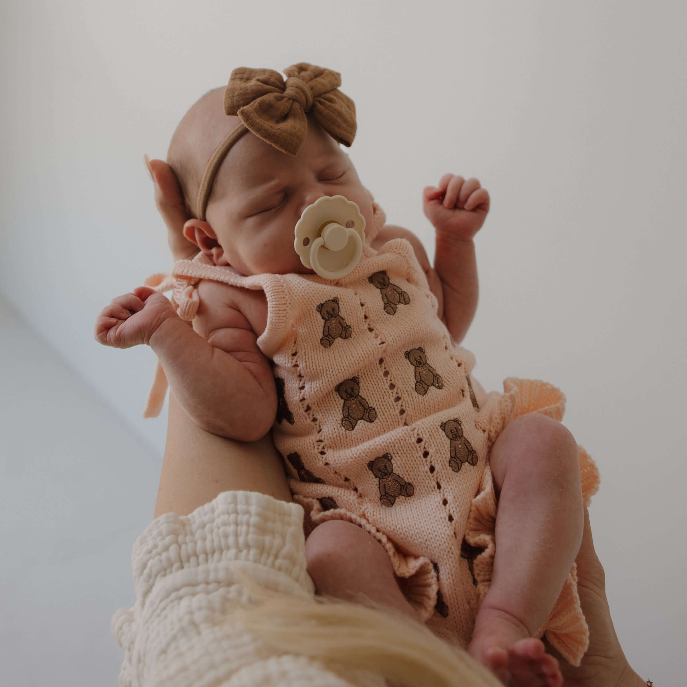 Lottie | Knit Ruffle Romper worn by a baby with teddy bear design and ruffle details | milk & baby