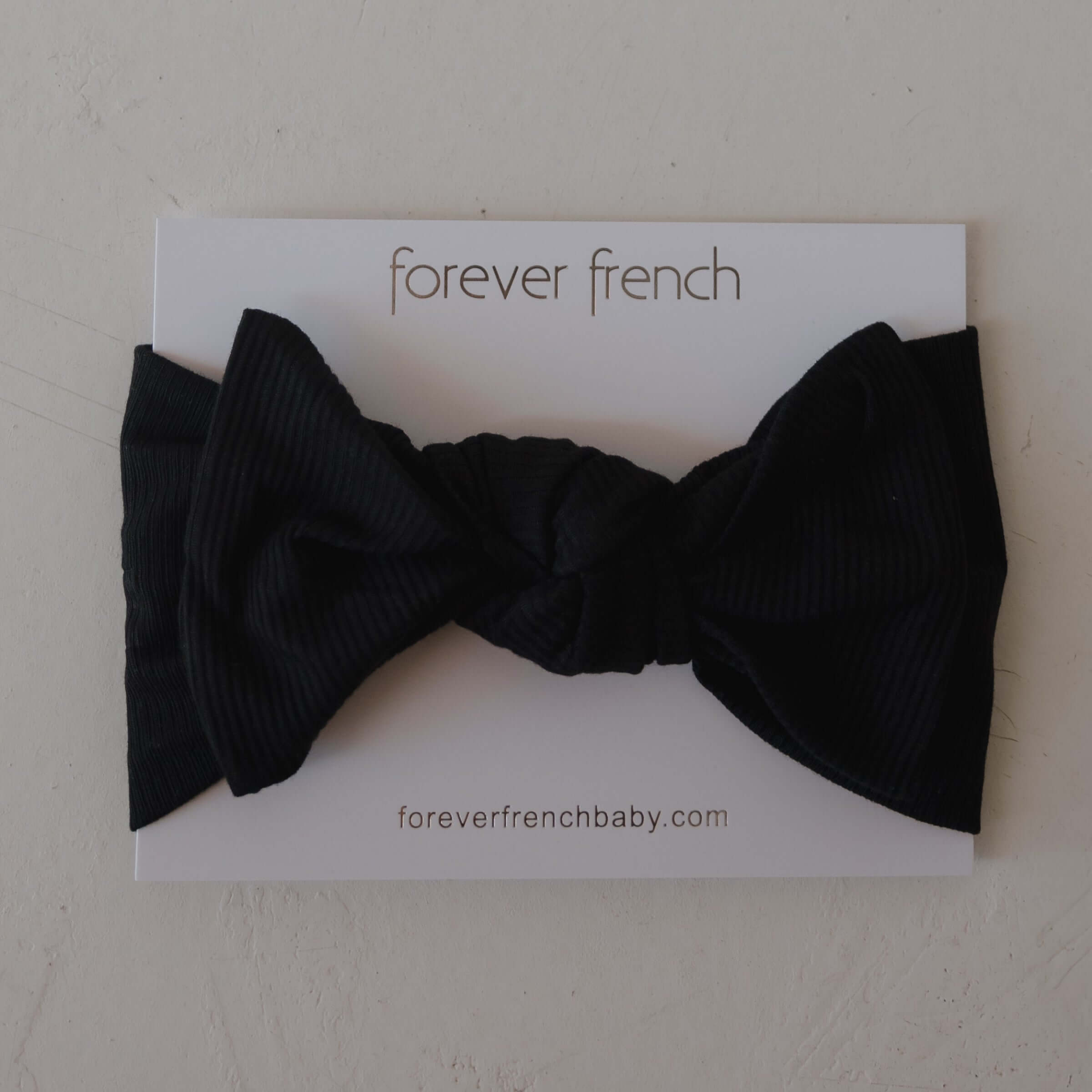 Black bow on a white card with 'forever french' branding