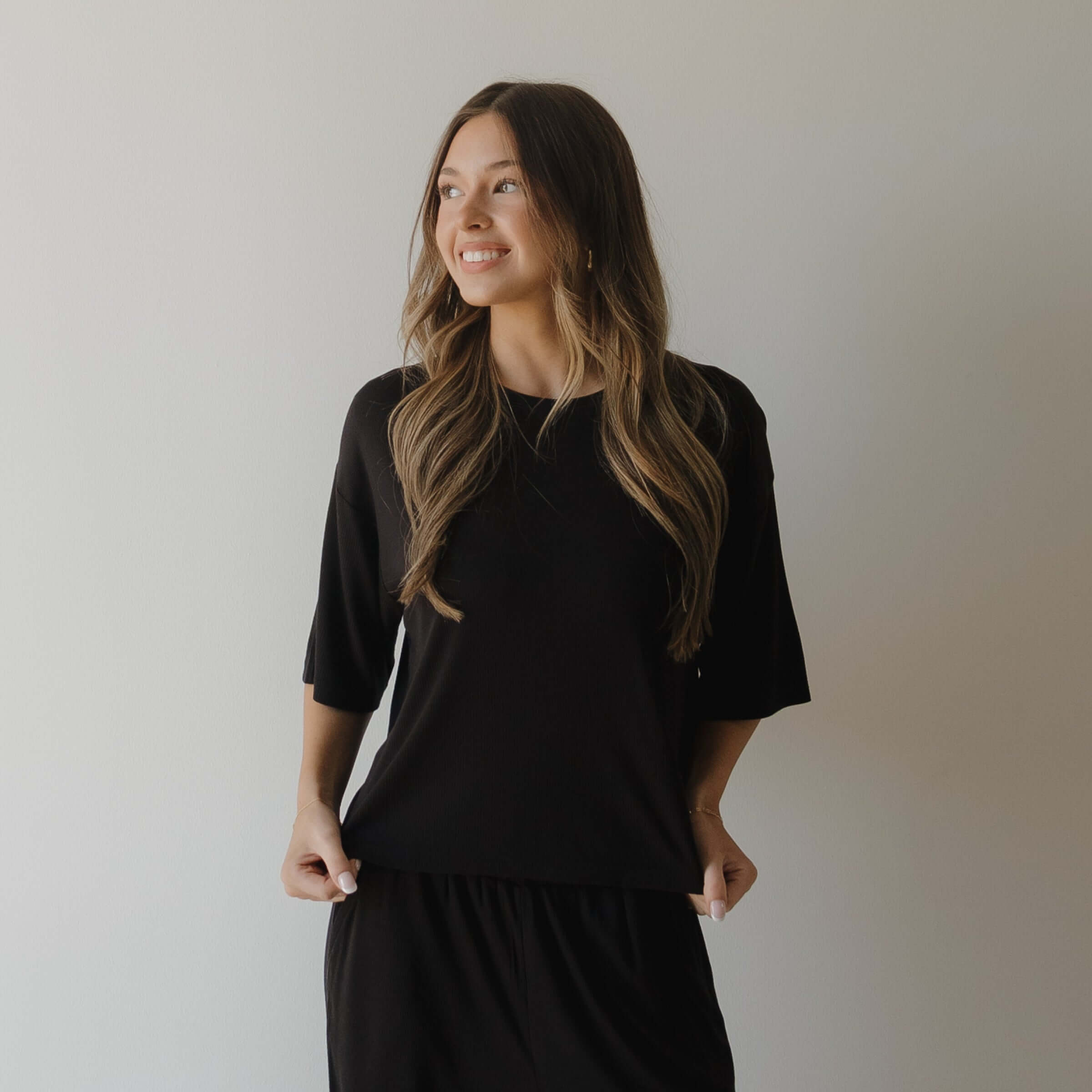Woman wearing black pajamas against a plain background