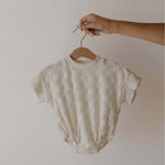Baby romper on a hanger against a plain background