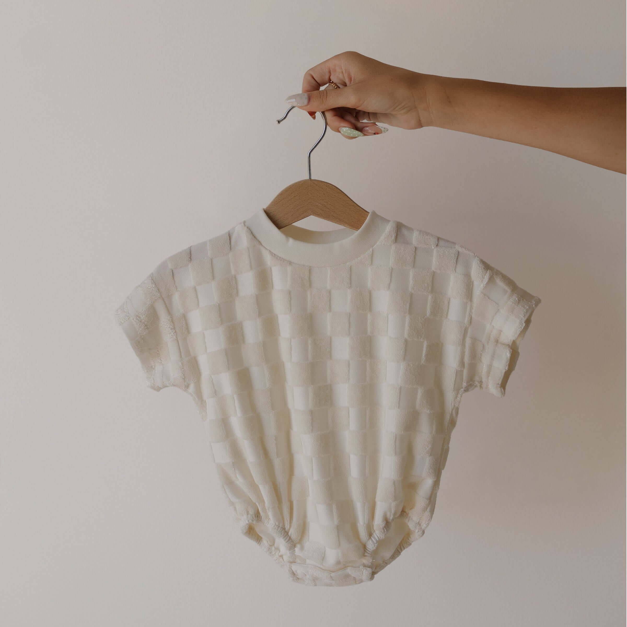 Baby romper on a hanger against a plain background