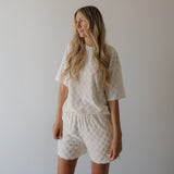 Woman wearing a white textured outfit against a plain background