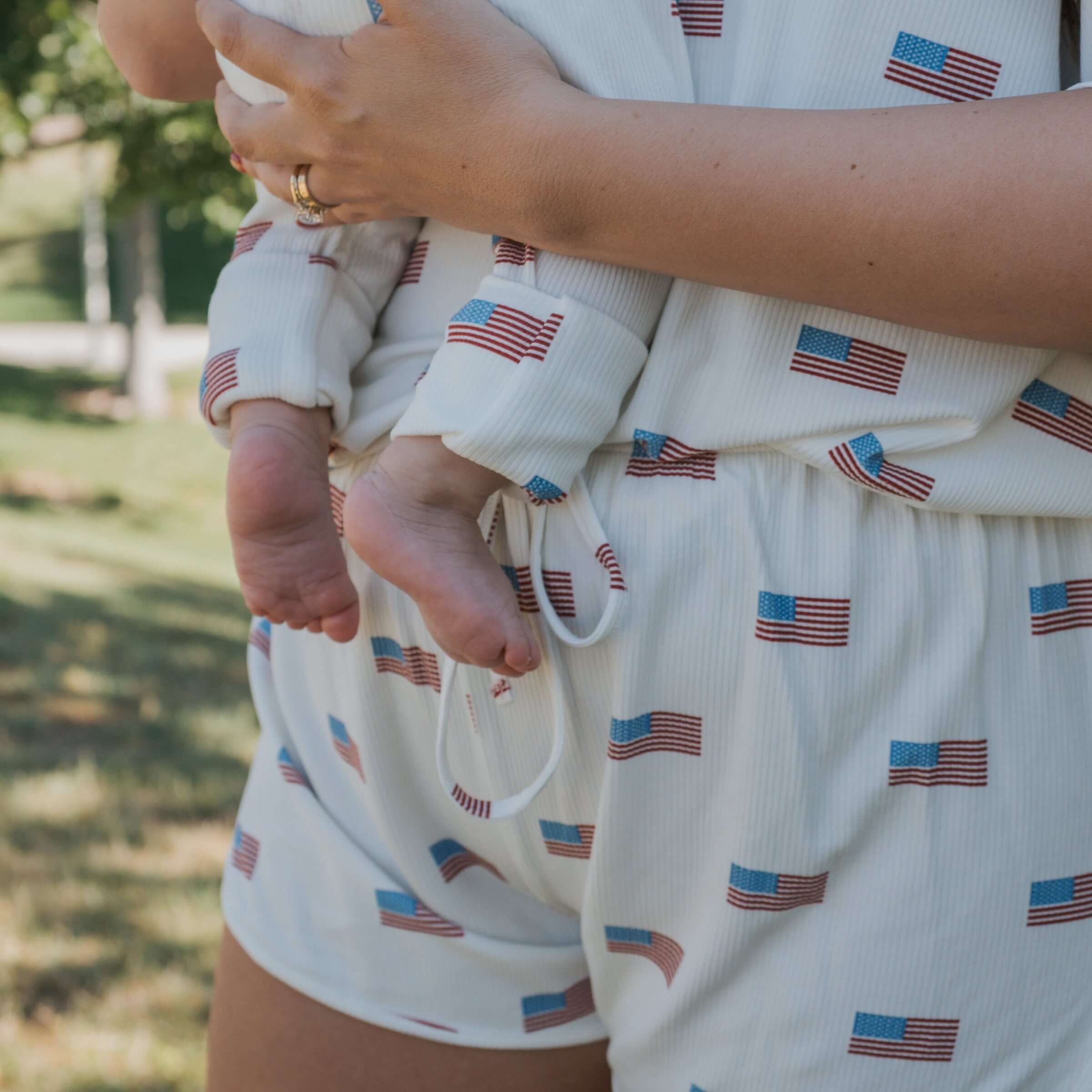 Mother holding baby in Americana | Ribbed Bamboo Zip Pajamas featuring a cute flag design.