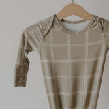Beige checkered baby gown on a wooden hanger against a plain background