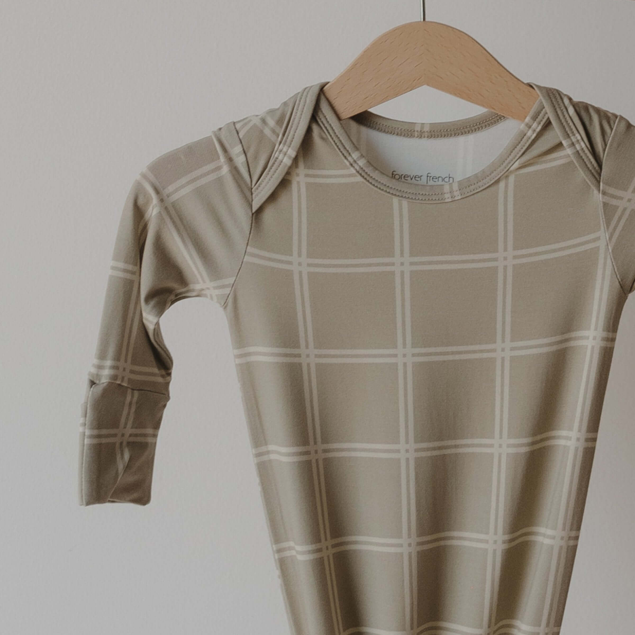 Beige checkered baby gown on a wooden hanger against a plain background