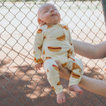 Baby wearing Hot Dogs | Bamboo Zip Pajamas, enjoying comfort and style on a sunny day.
