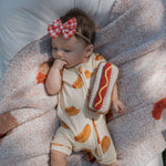 Baby enjoying summer with a Knit Rattle | Hot Dog in a cozy outfit and a stylish bow headband.