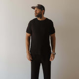Man wearing a black pajamas with a cap against a plain background