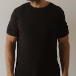 Person wearing a plain black pajamas against a neutral background