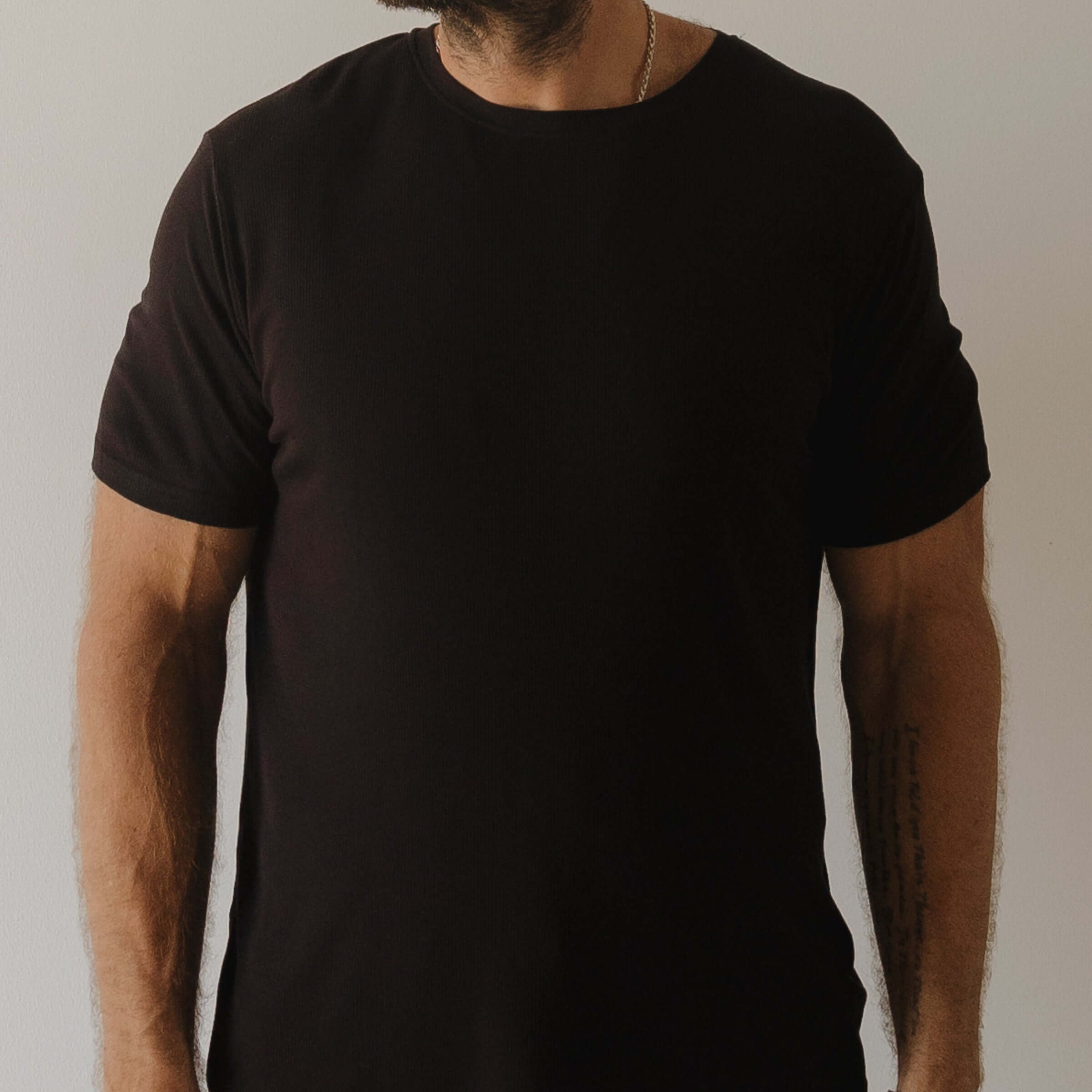 Person wearing a plain black pajamas against a neutral background