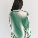 Person wearing a green and white striped shirt on a plain background