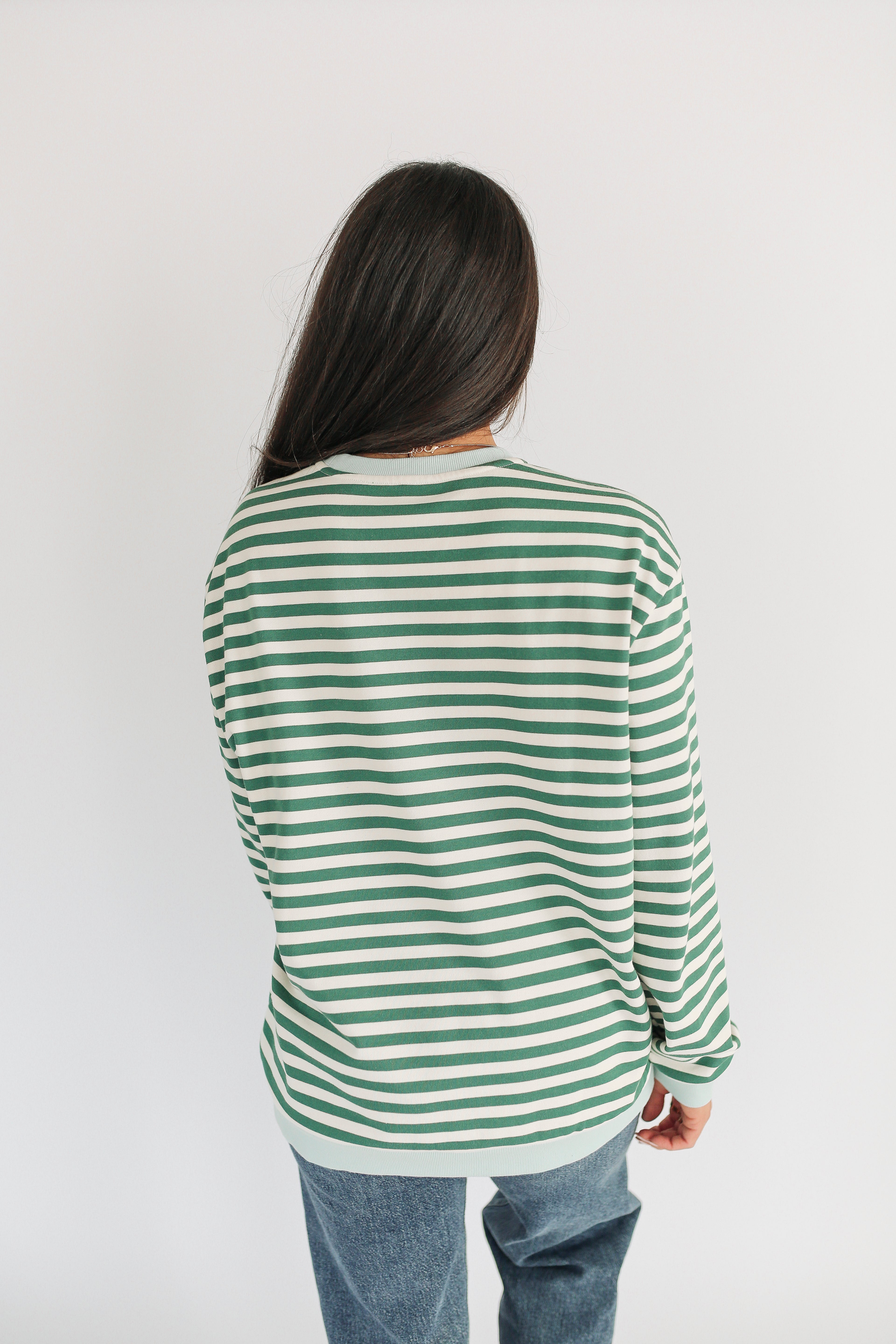 Person wearing a green and white striped shirt on a plain background