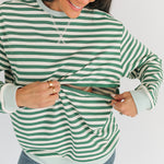 Woman wearing a green and white striped sweater with a plain background