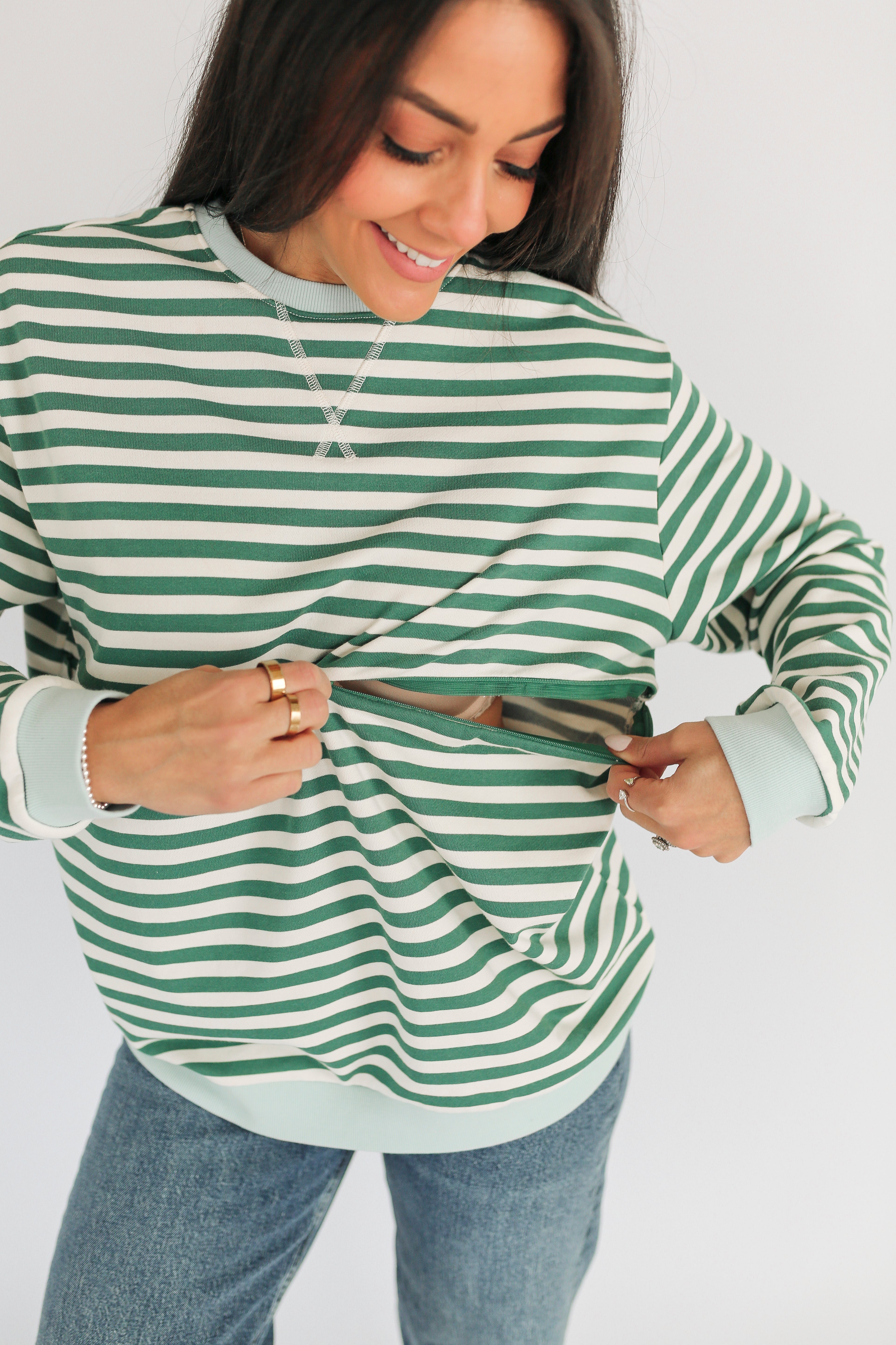 Woman wearing a green and white striped sweater with a plain background