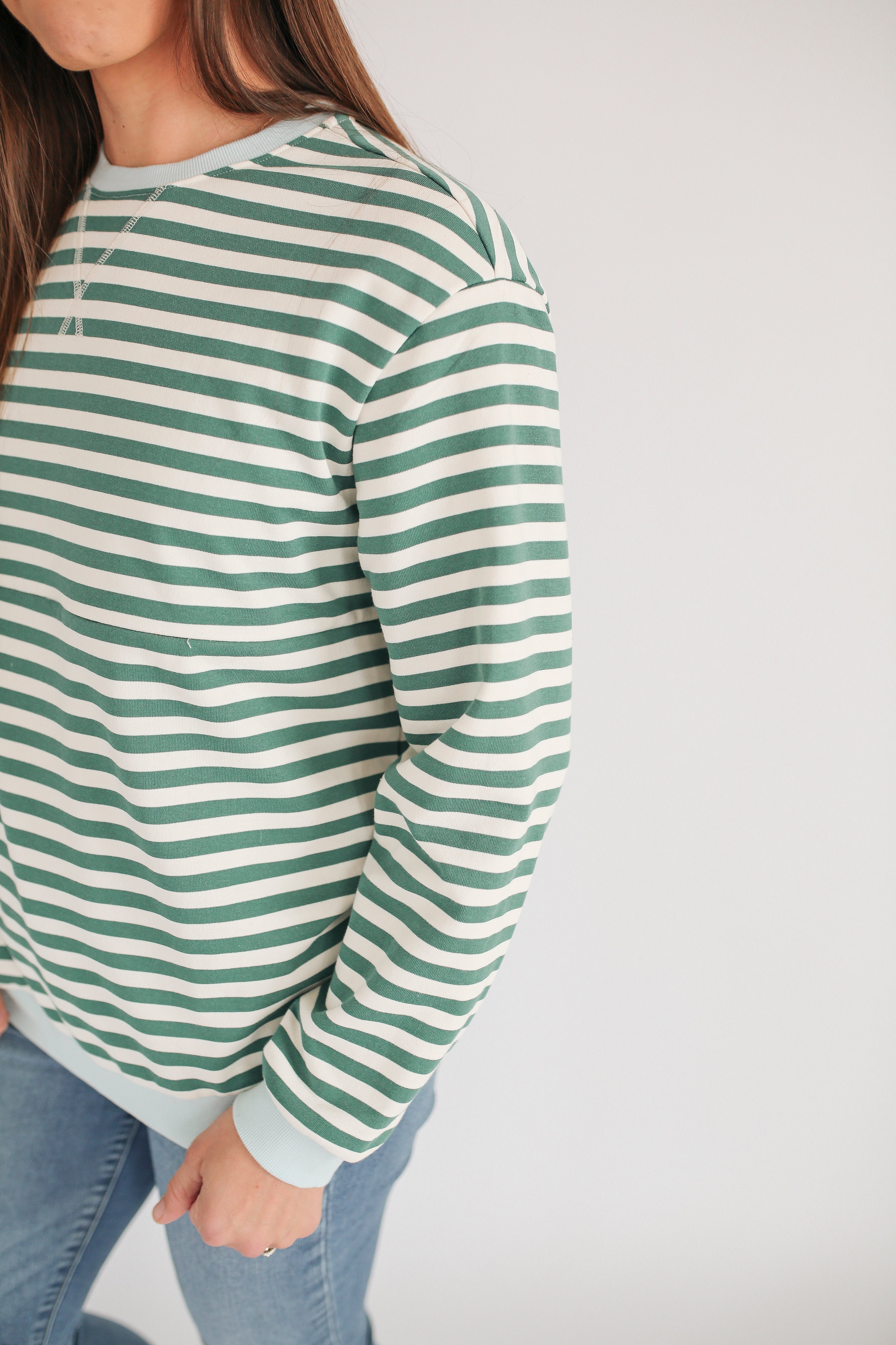 Woman wearing an oversized fit freestyle stripe breastfeeding sweatshirt in green and white.