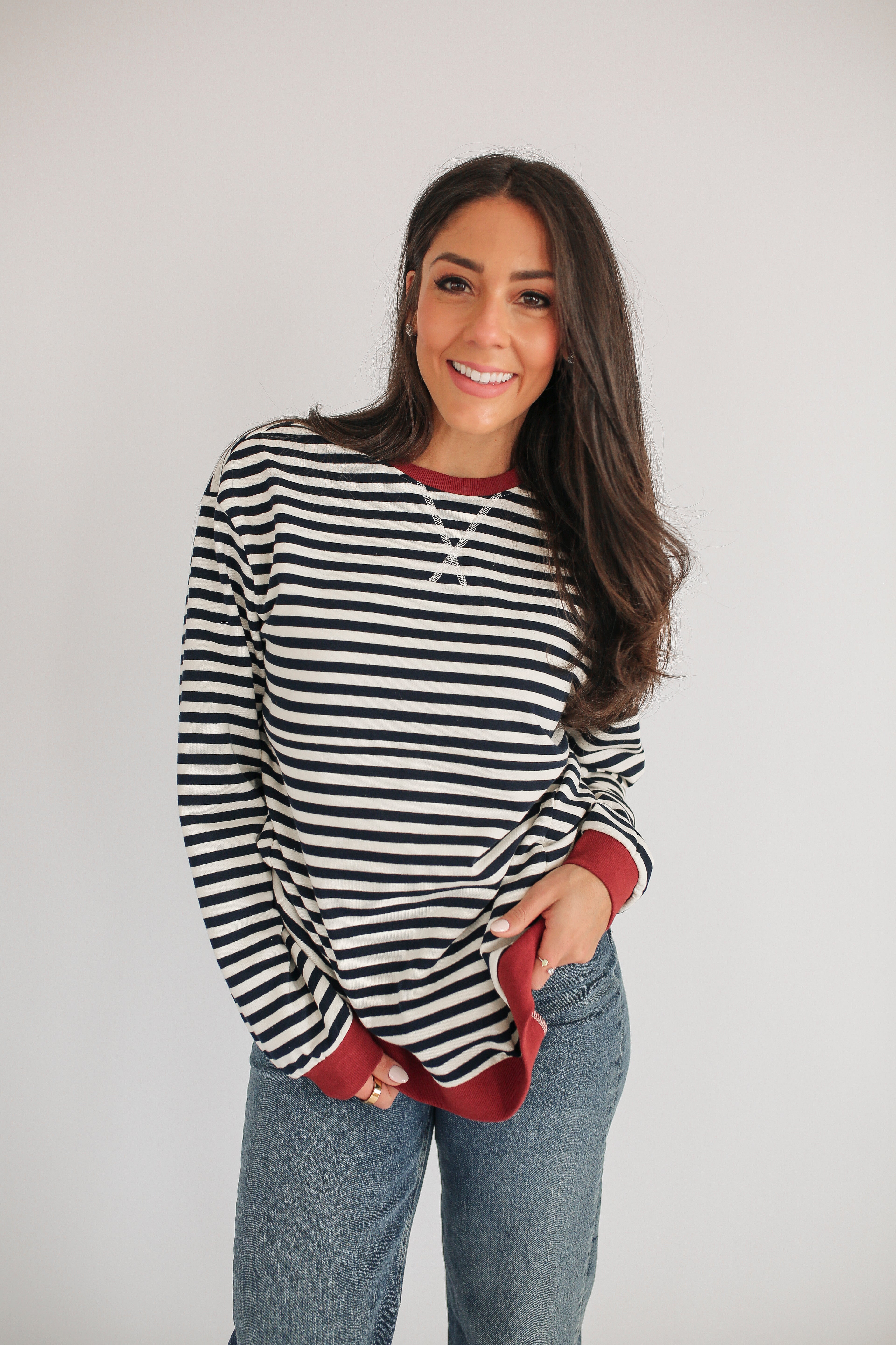 Woman wearing a black and white striped shirt with red accents on a plain background