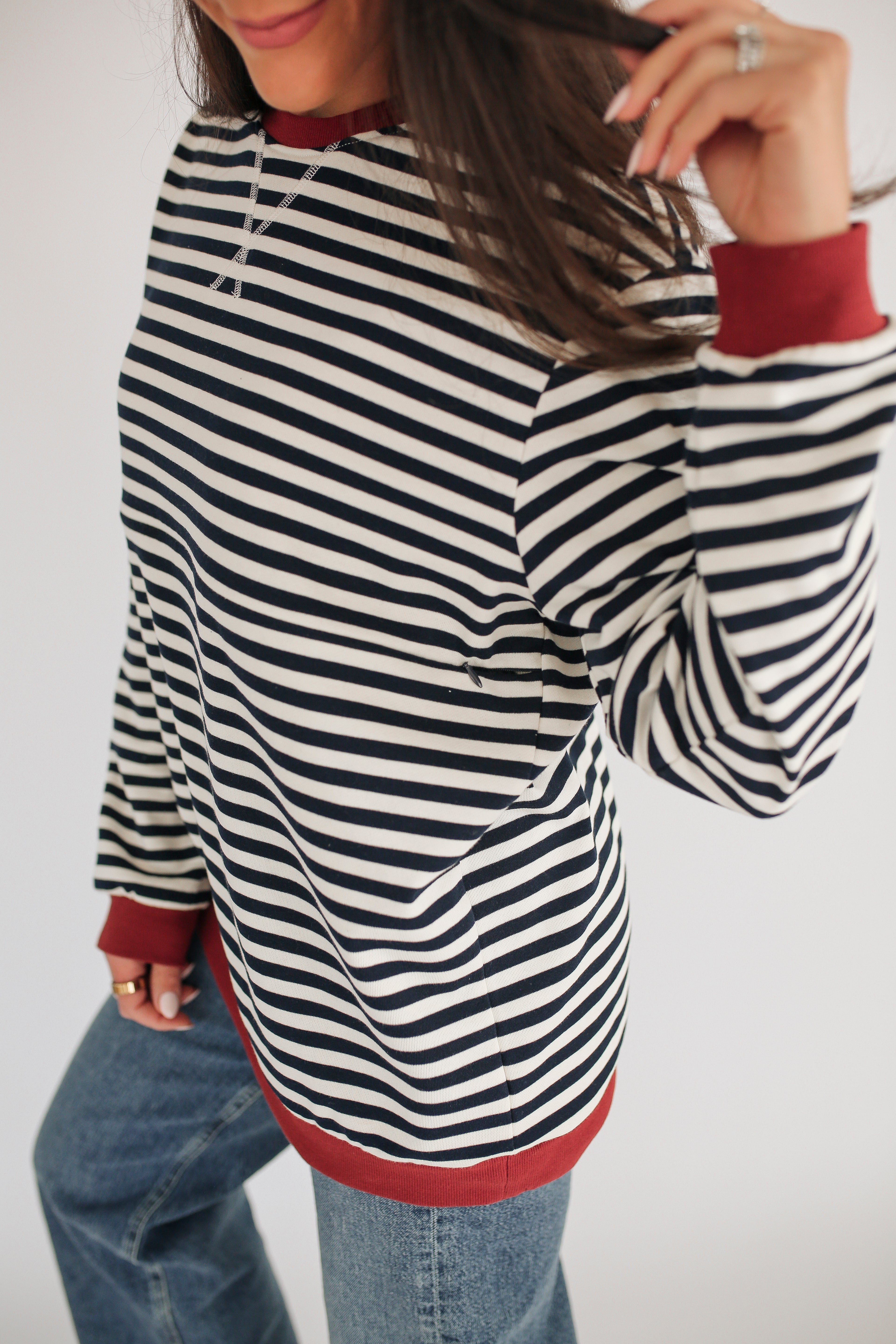 Person wearing a black and white striped sweater with red trim on a plain background