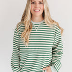 Woman wearing a green and white striped sweater against a plain background