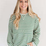 Woman wearing a green and white striped sweater against a plain background