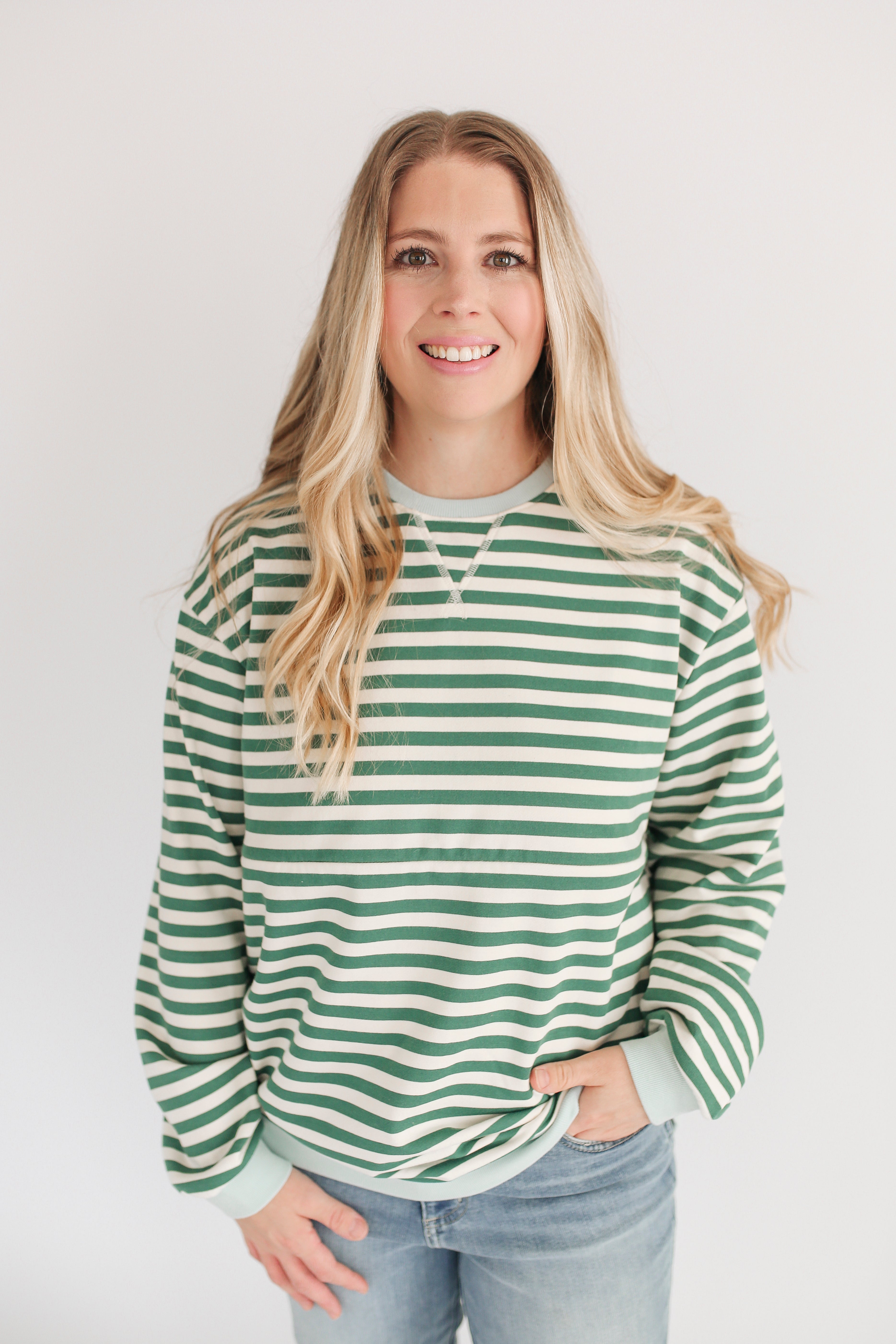 Woman wearing a green and white striped sweater against a plain background