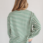 Person wearing a green and white striped shirt with a plain background