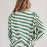 Person wearing a green and white striped shirt with a plain background