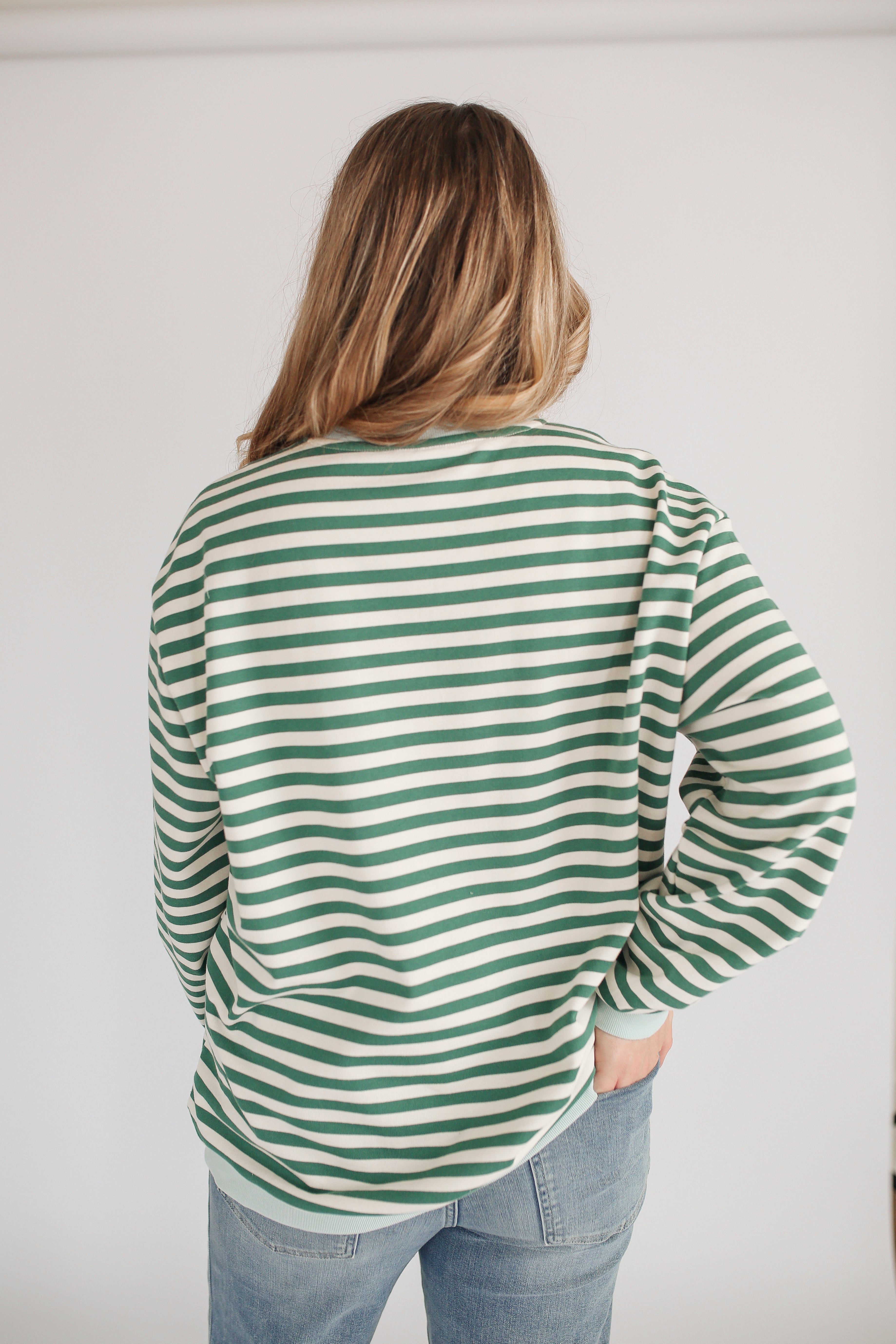Person wearing a green and white striped shirt with a plain background