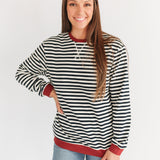 Woman wearing a black and white striped sweater with red trim on a white background