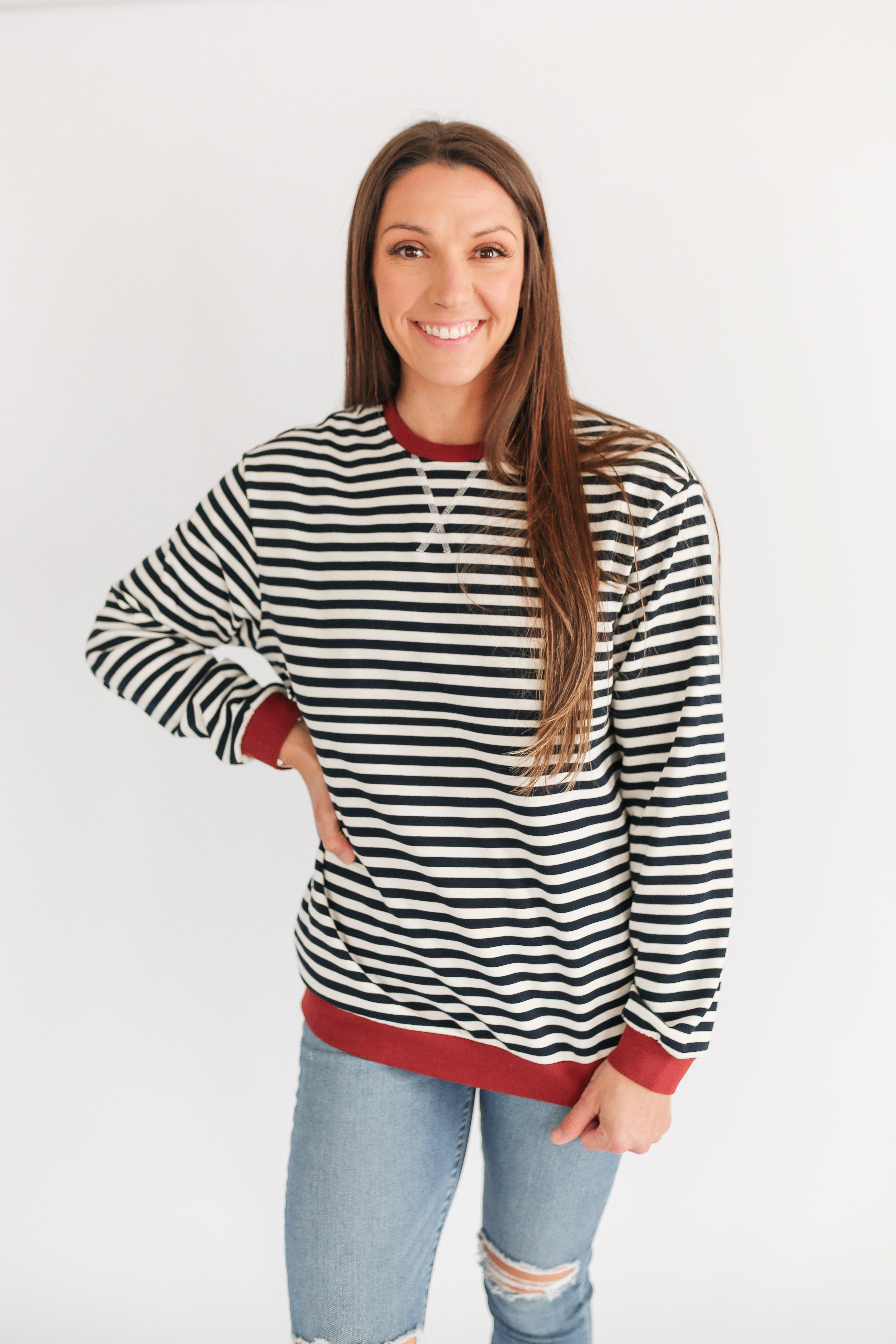 Woman wearing a black and white striped sweater with red trim on a white background