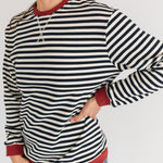 Woman wearing a striped long-sleeve shirt with red trim on a white background