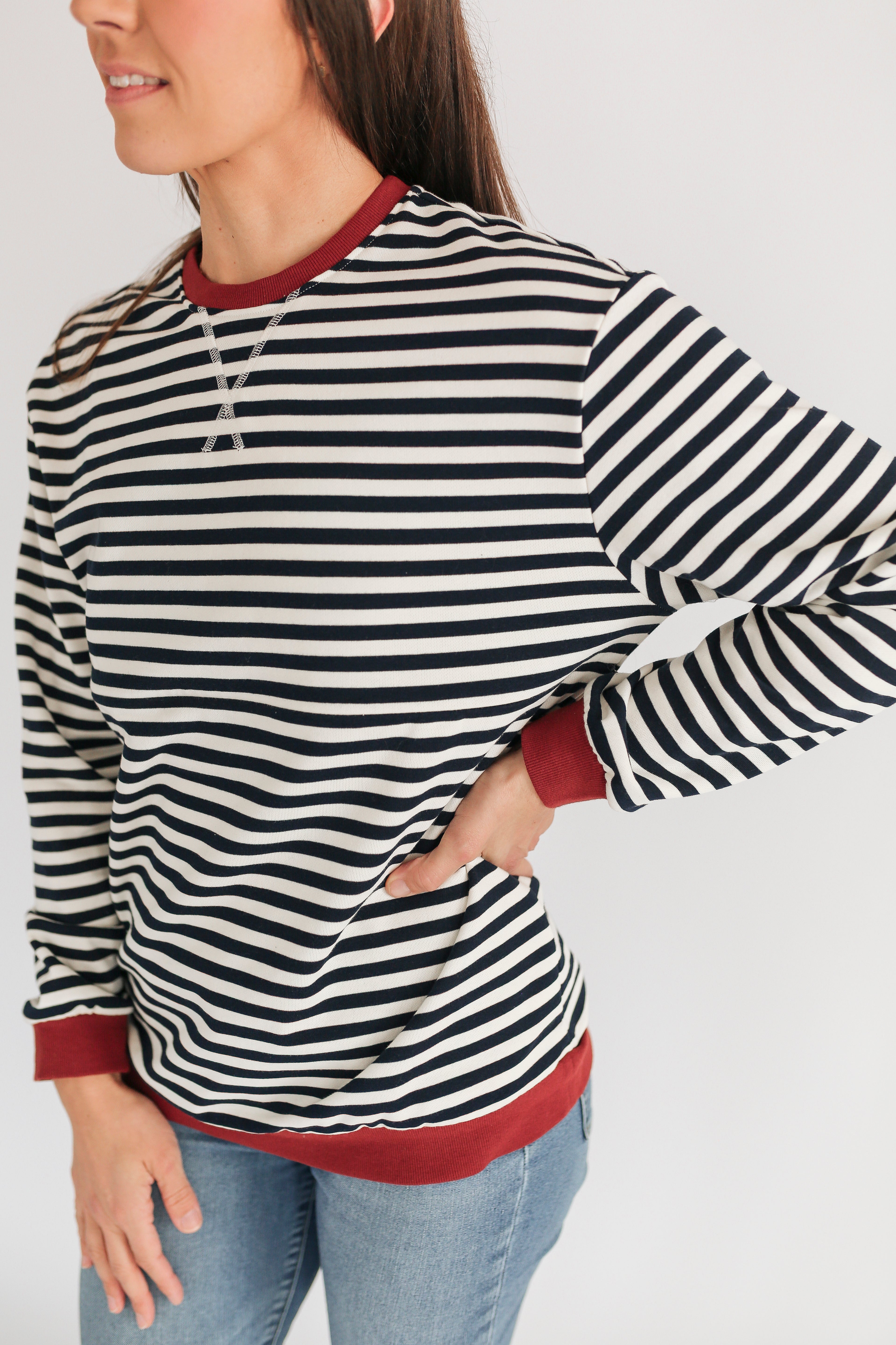 Woman wearing a striped long-sleeve shirt with red trim on a white background