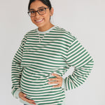 Woman wearing a green and white striped sweater on a plain background