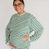 Woman wearing a green and white striped sweater on a plain background