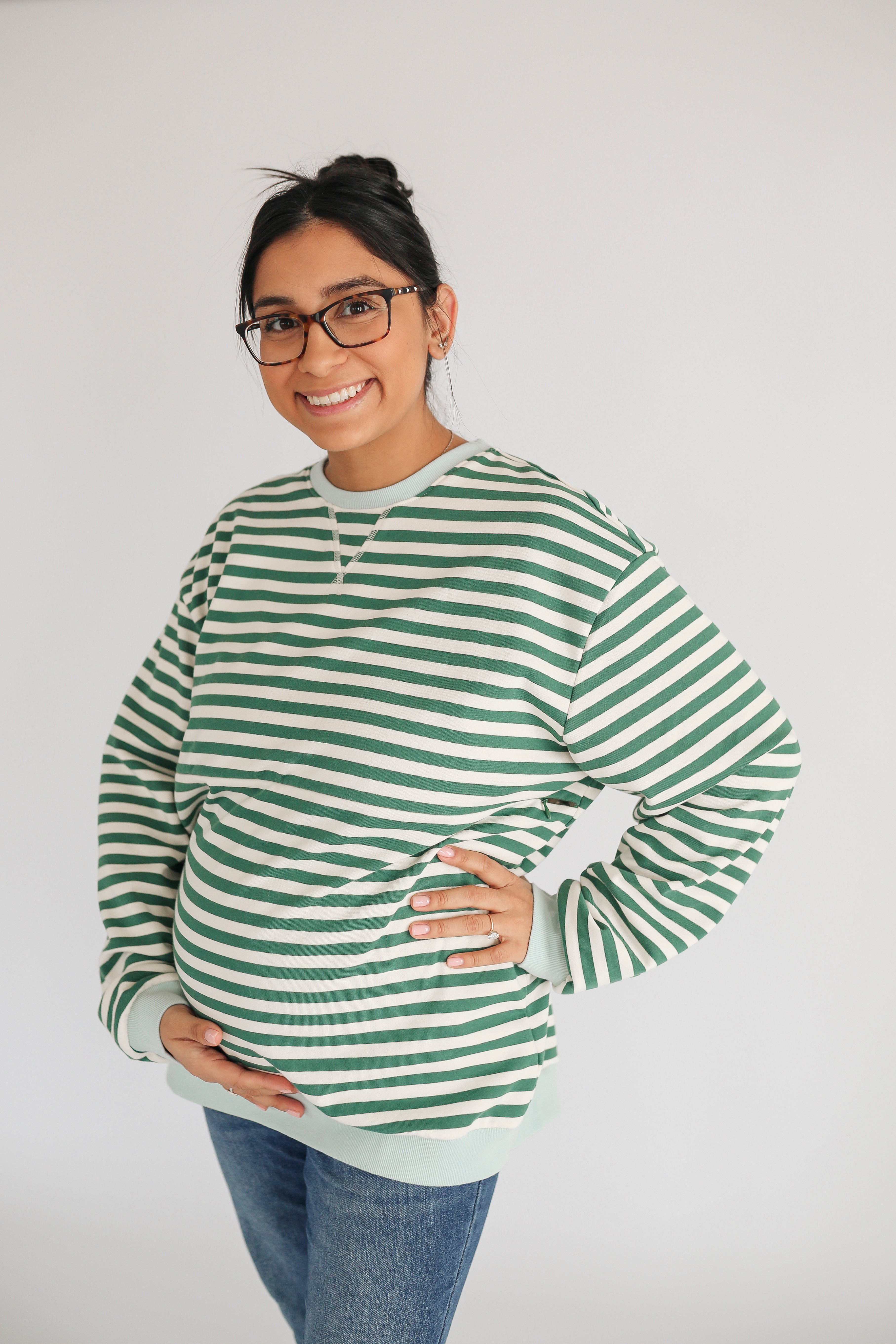 Woman wearing a green and white striped sweater on a plain background
