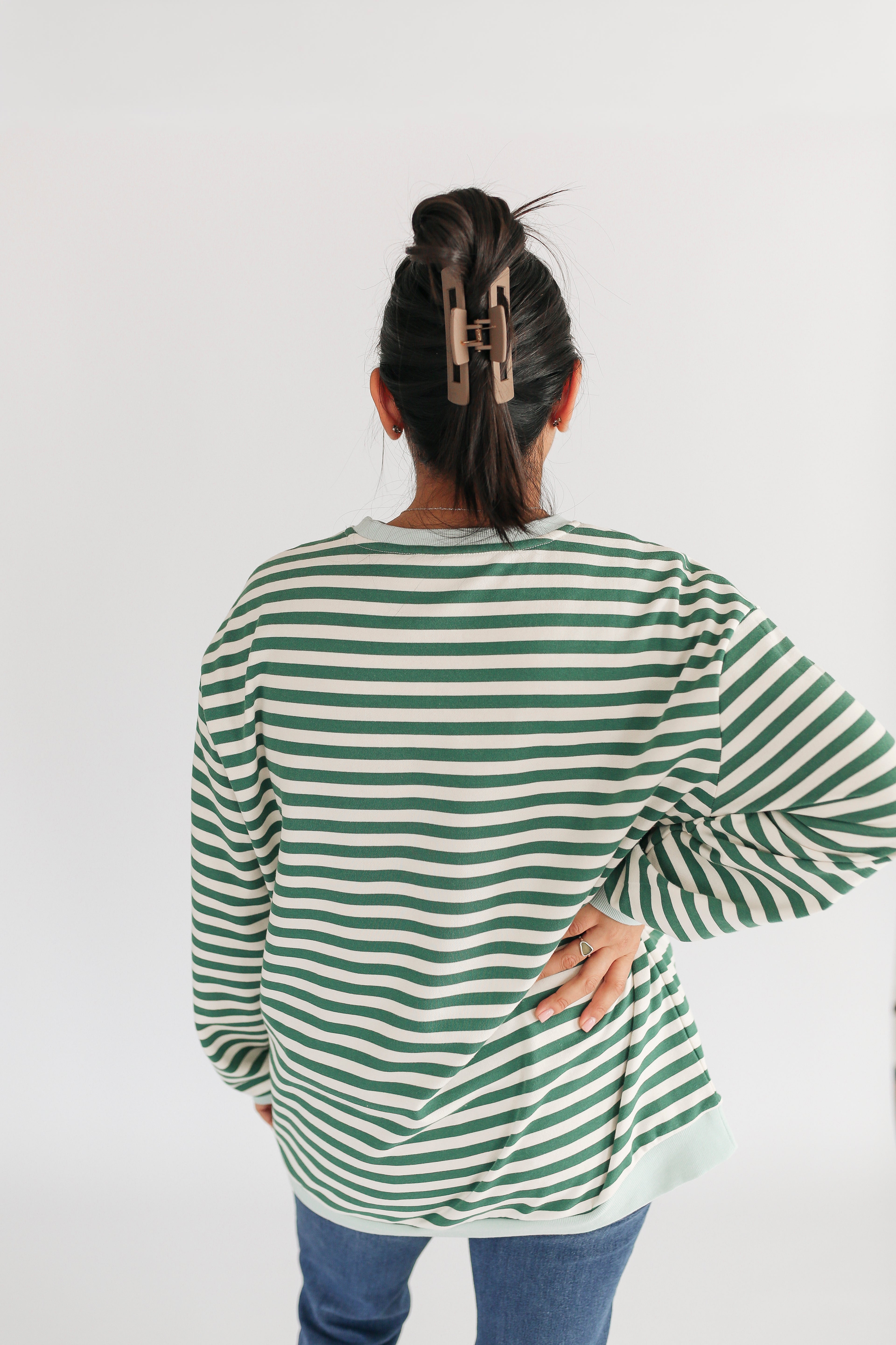 Person wearing a green and white striped shirt on a plain background