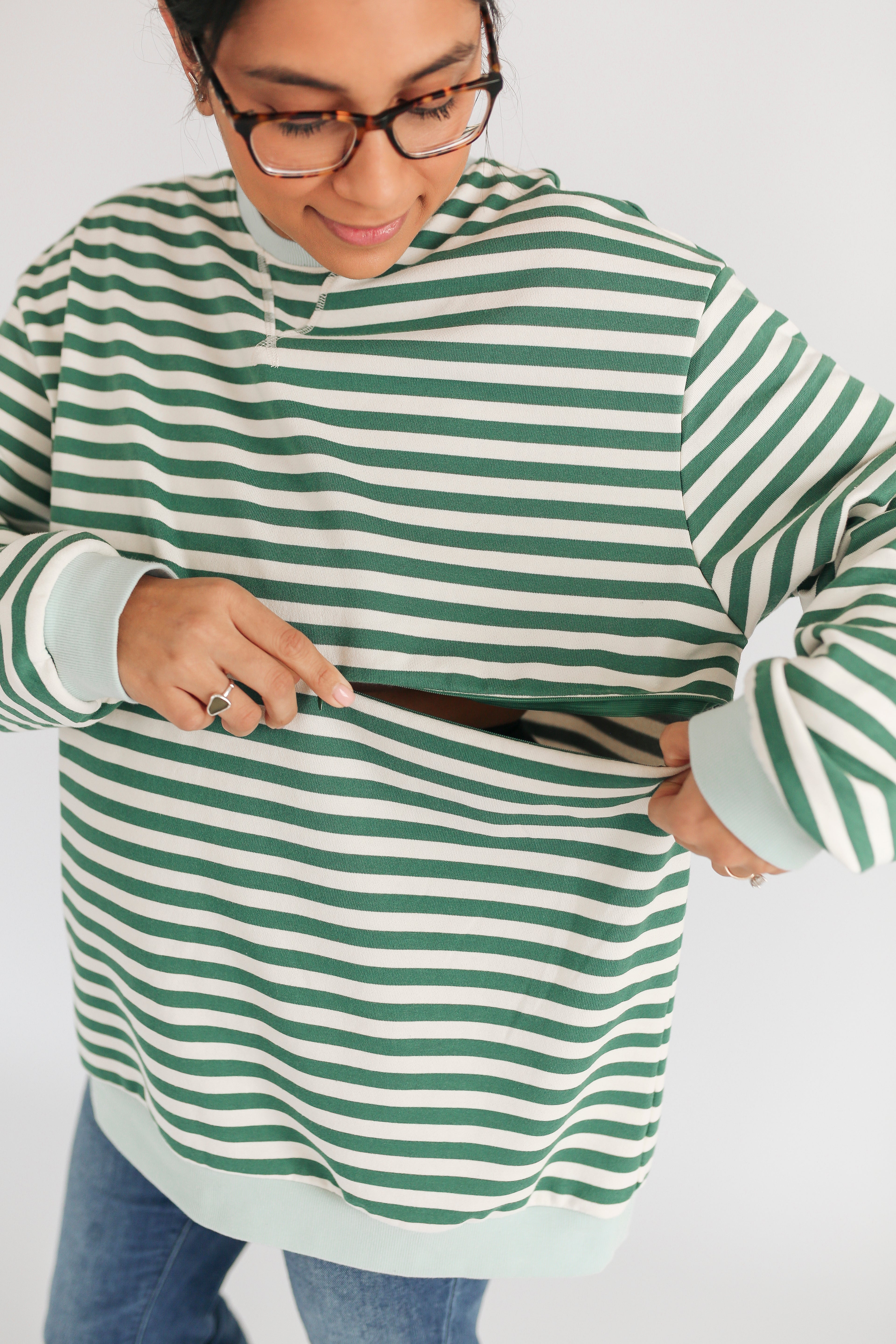 Person wearing a green and white striped sweater on a plain background