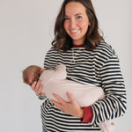 Woman holding a baby against a plain background
