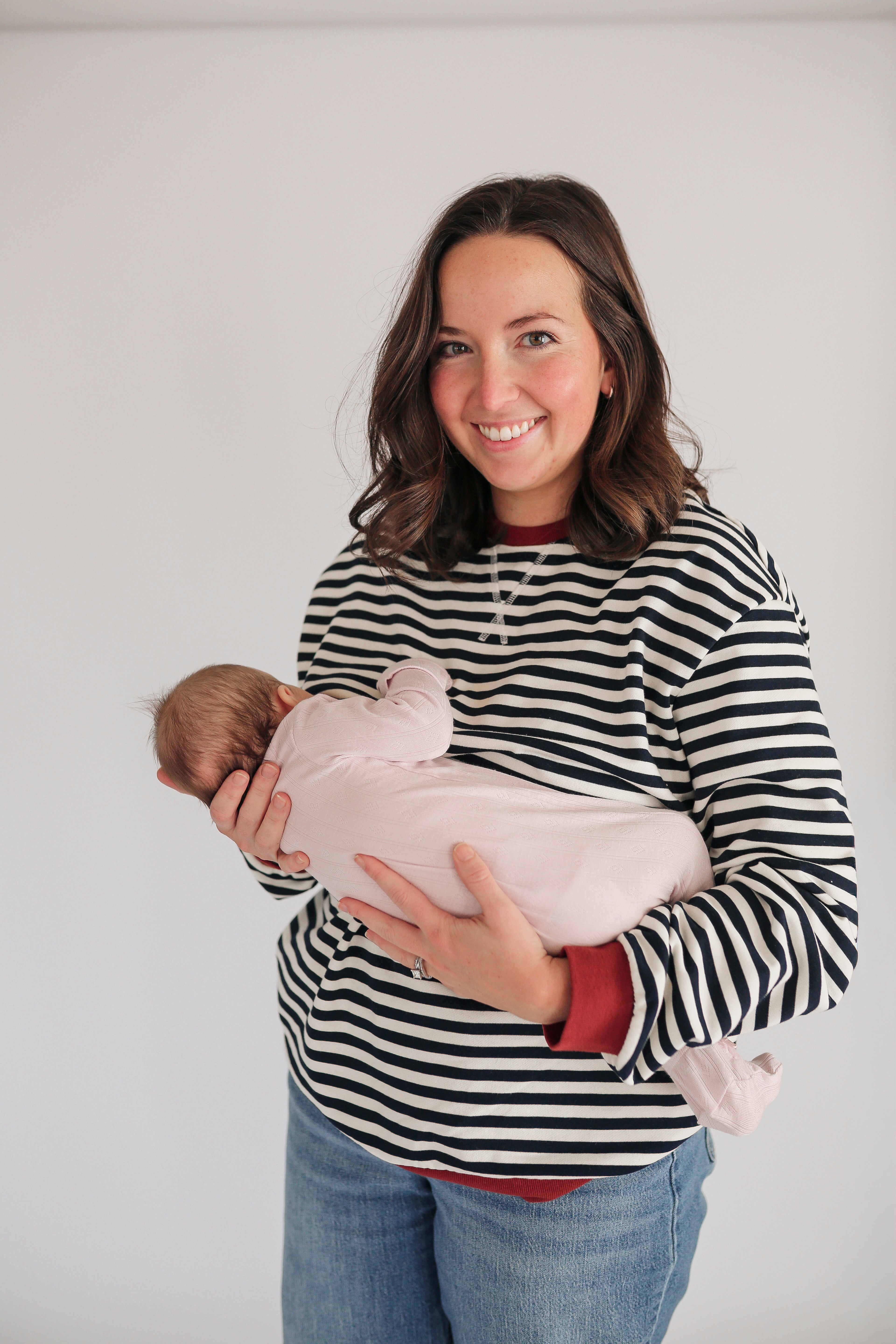 Woman holding a baby against a plain background