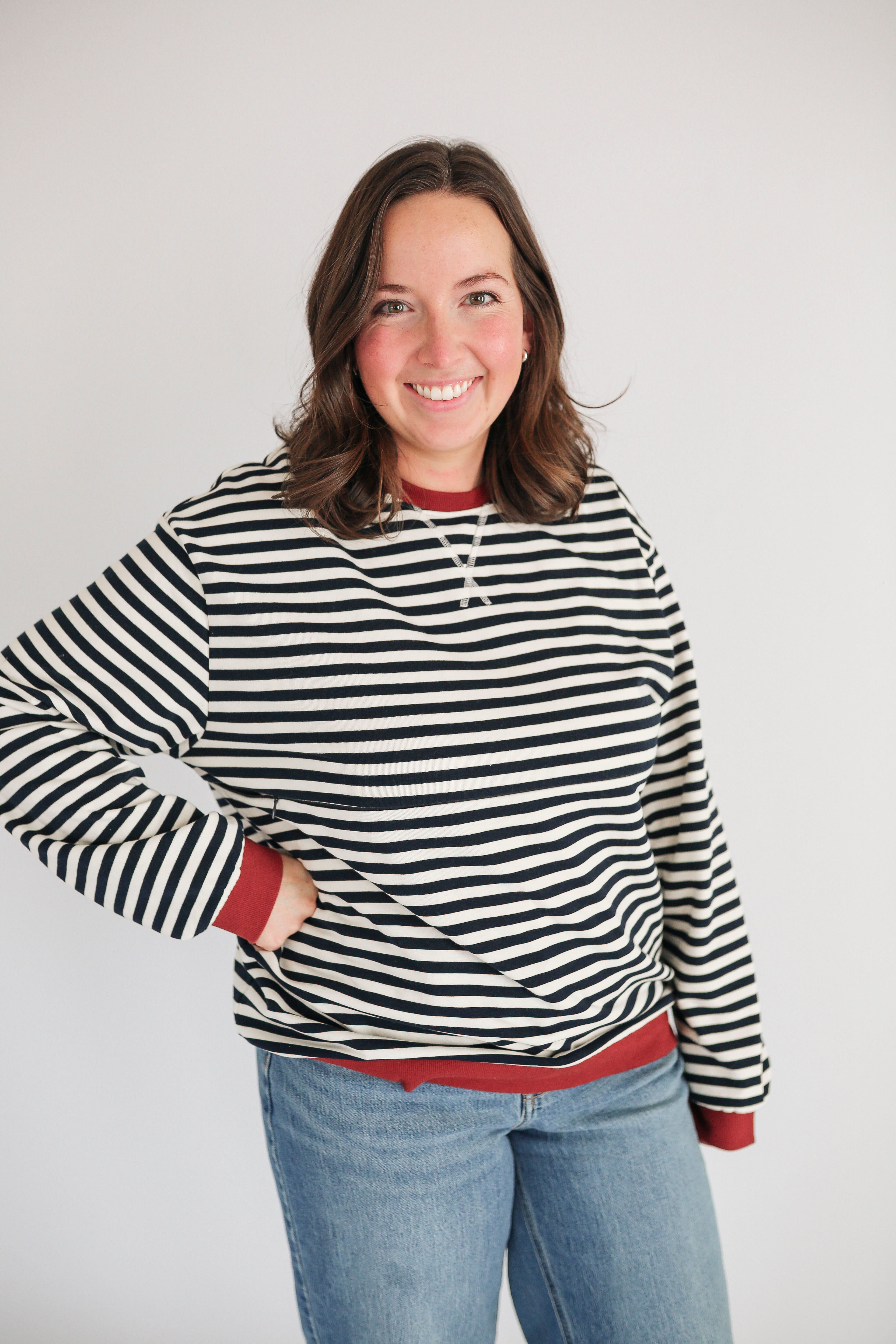 Woman wearing an oversized fit freestyle stripe breastfeeding sweatshirt with a smile.