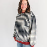 Person wearing a black and white striped hoodie with red trim on a white background