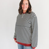 Person wearing a black and white striped hoodie with red trim on a white background
