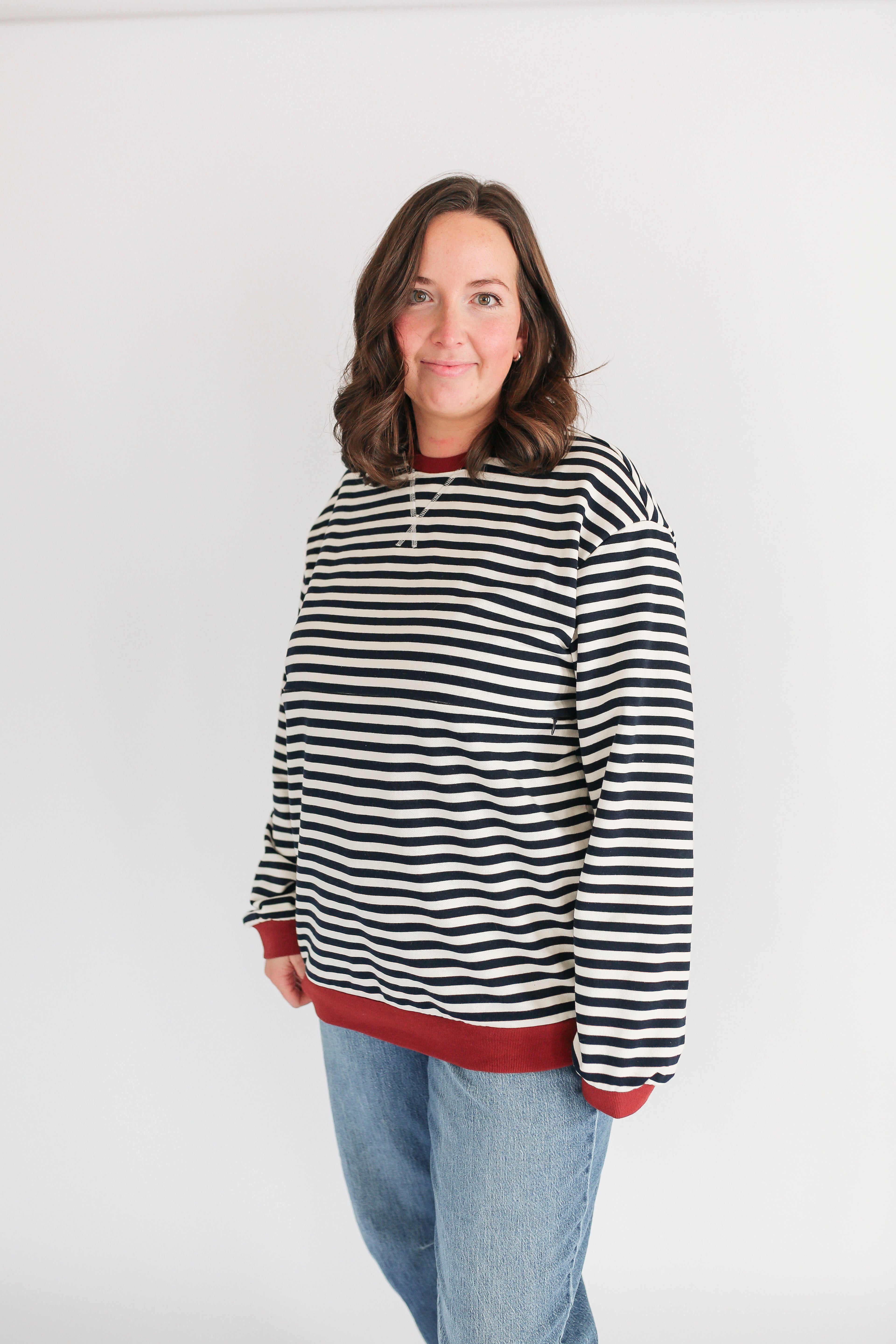Person wearing a black and white striped hoodie with red trim on a white background