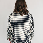 Person wearing a black and white striped shirt with red trim on a plain background