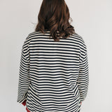 Person wearing a black and white striped shirt with red trim on a plain background