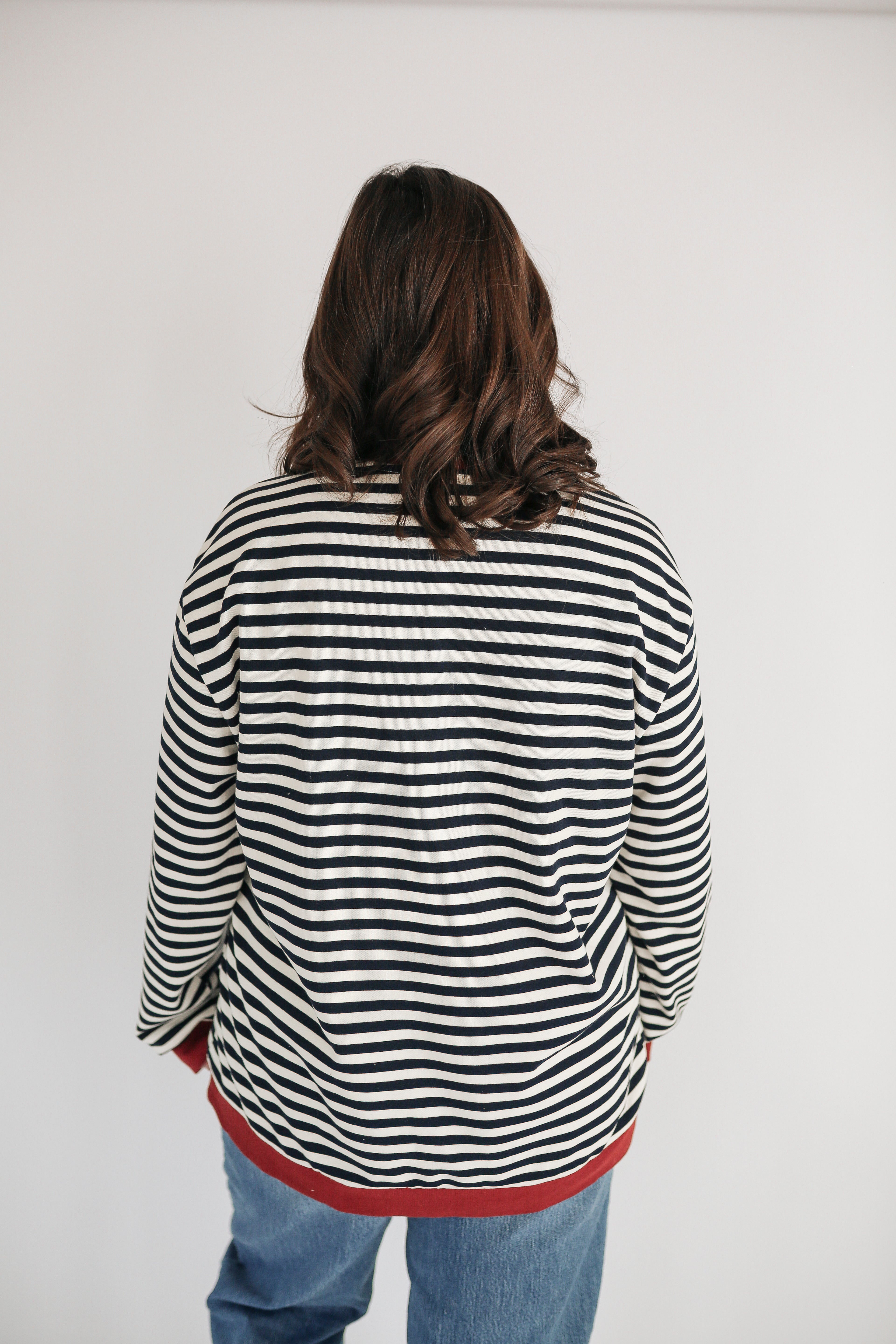 Person wearing a black and white striped shirt with red trim on a plain background