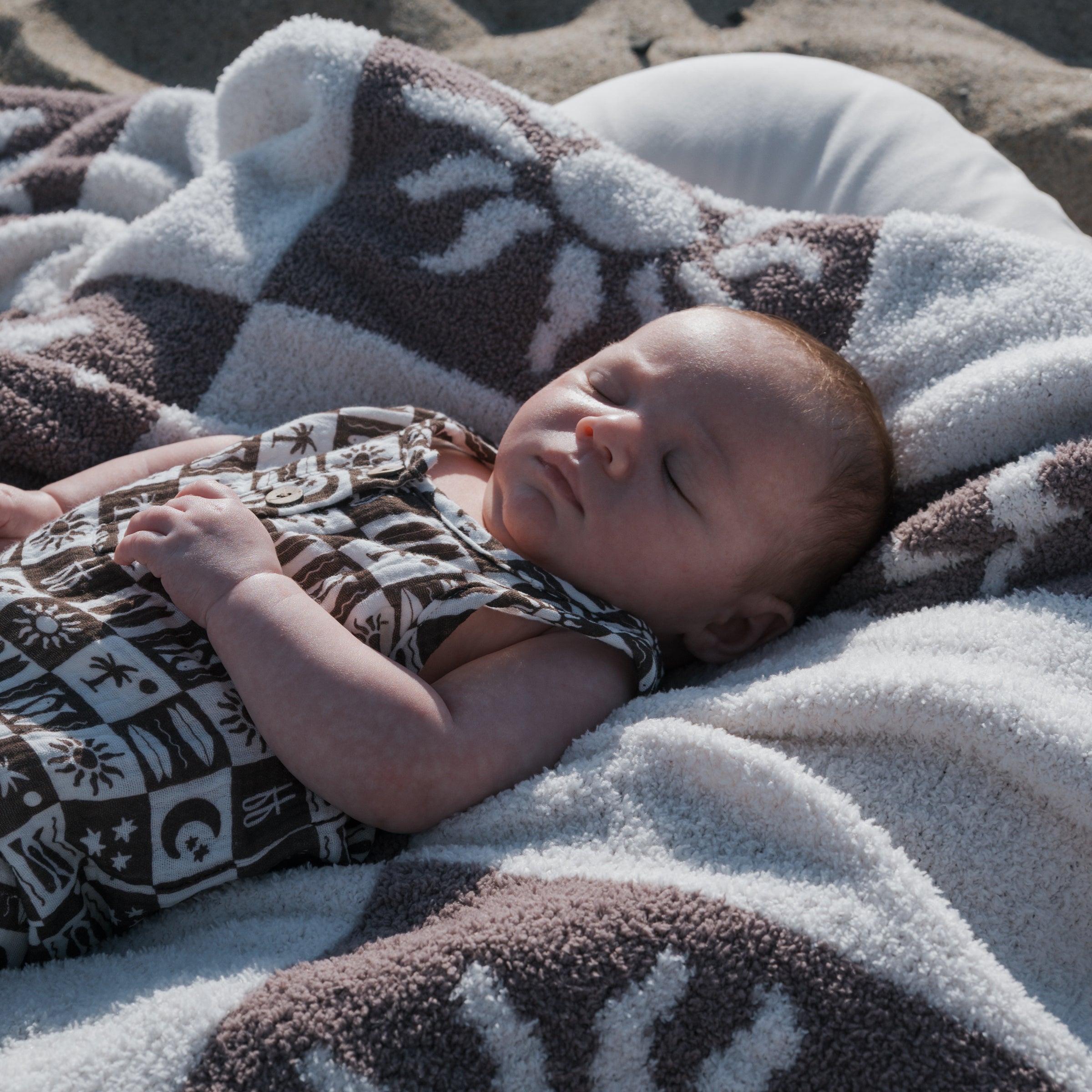 Baby peacefully sleeping on a blanket, wearing a Summer Check | Muslin Tank Romper.