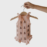 Lottie | Knit Ruffle Romper hanging on a wooden hanger, featuring embroidered teddy bears and ruffled details | milk & baby